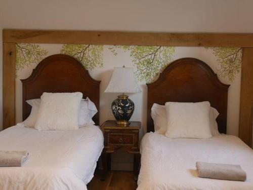 two beds with white sheets and a lamp on a table at Cheltenham accommodation -self-catering-2 bedrooms in Cheltenham