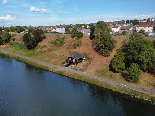 a house on the side of a road next to a river at Chalet le logis des autre in Vireux-Wallerand
