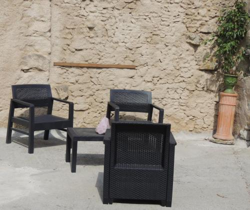 two chairs and a table in front of a stone wall at Les treilles d'en Peyre in Nogaret