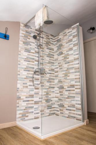 a shower in a room with a stone wall at B&B Miellò nelle Langhe in Mango