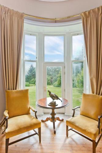 a living room with two chairs and a table and a window at Dalnaglar Castle in Blairgowrie