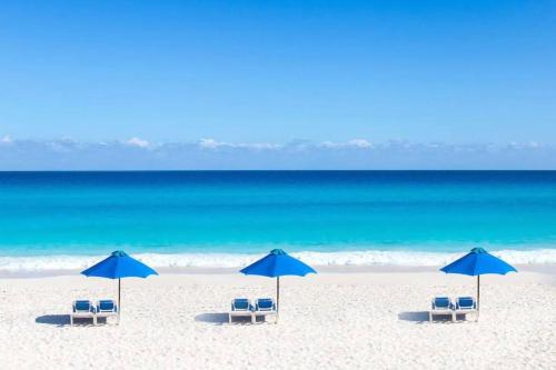 een groep stoelen en parasols op een strand bij Villas Marlin by Andiani Travel in Cancun