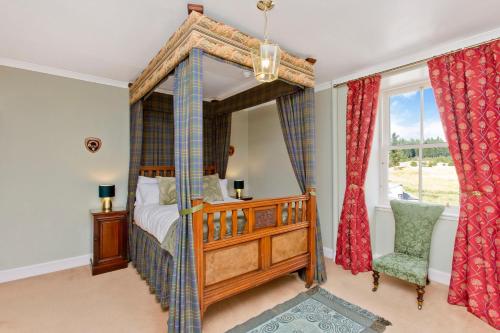 a bedroom with a canopy bed and a chair at Dalnaglar Castle in Blairgowrie