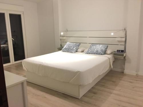 een slaapkamer met een groot wit bed met blauwe kussens bij Acogedor y Luminoso piso con balcón in Arona