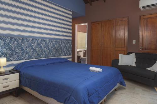 um quarto com uma cama azul e um sofá em Hotel Nuevo Suizo em San Juan