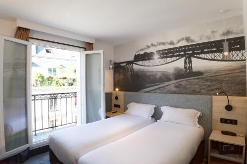 two beds in a room with a large window at Appia La Fayette in Paris