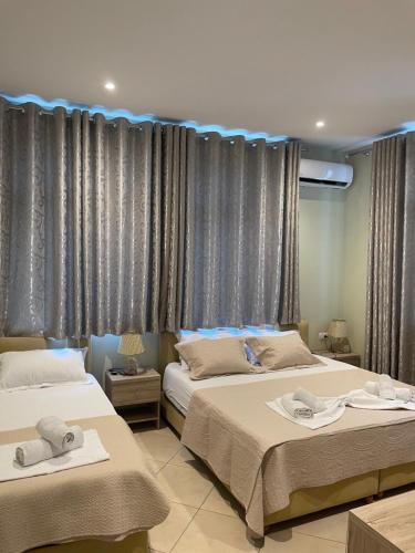 2 Betten in einem Zimmer mit Vorhängen in der Unterkunft Deni's Hotel in Sarandë