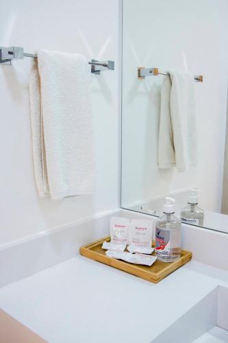a bathroom with a mirror and a tray with products on it at Ramada Hotel & Suites Campos Pelinca in Campos dos Goytacazes