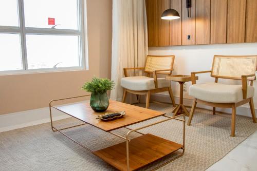 a living room with a coffee table and chairs at Ramada Hotel & Suites Campos Pelinca in Campos dos Goytacazes