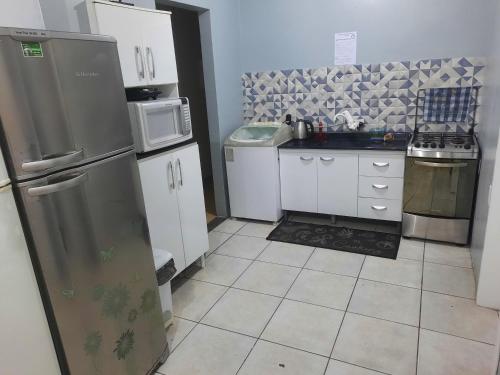 a small kitchen with white cabinets and a refrigerator at Suíte Azul com SmartTv, Cama Queen e Banheiro Privativo in Itajaí