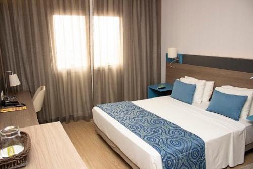 a bedroom with a large bed with blue and white sheets at Hilton Garden Inn Santo Andre in Santo André