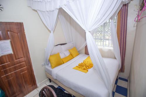a bedroom with a bed with yellow pillows and a window at Happy Springs Hotel & Accomodation in Kericho