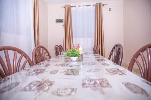 a dining room table with a white table cloth and chairs at Happy Springs Hotel & Accomodation in Kericho