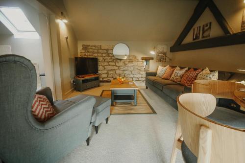 a living room with a couch and a tv at Vicarage Farm Cottages in Tideswell