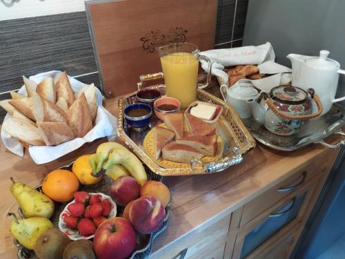 - une table de petit-déjeuner avec des fruits, du pain et un verre de jus d'orange dans l'établissement Gite Esprit du Monde, à Kervignac