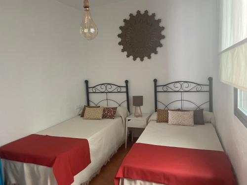 1 dormitorio con 2 camas y lámpara de araña en Apartamento Reina Mercedes Centro-Playa WIFI GRATIS, en Chipiona