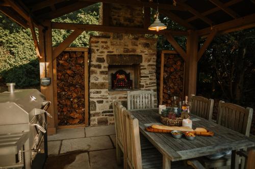 a wooden table on a patio with a fireplace at Vicarage Farm Cottages in Tideswell