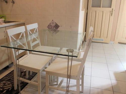 a glass table and white chairs in a kitchen at Sonnenberg-Villa Brunner Apartments in Budapest
