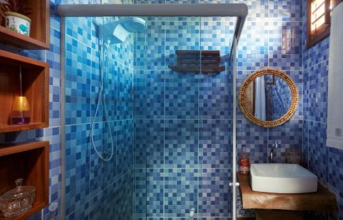 a blue tiled bathroom with a shower and a sink at Pousada Casa Zê - Praia do Preá in Prea