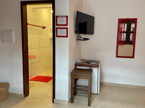a room with a small table and a tv on a wall at Pousada Atlantis in Jericoacoara