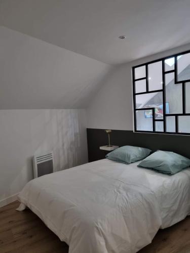 a white bedroom with a large bed with two pillows at Petit Nid Douillet in Solre-le-Château