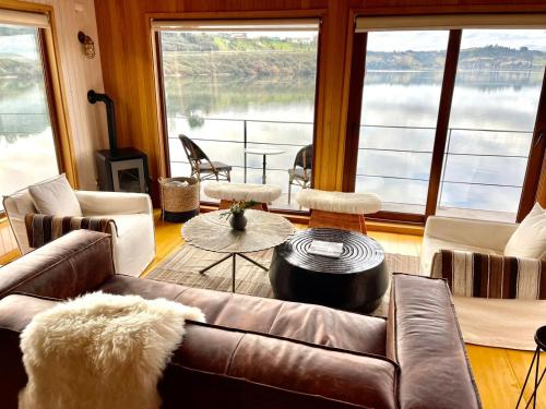 a living room with a leather couch and a large window at Bledford Chiloé in Castro