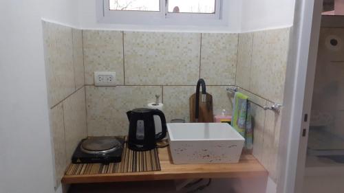 um balcão de cozinha com um lavatório e comodidades para preparar café em Alojam Las Heras 10 Off Termas em Villa Elisa