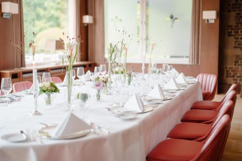 a long table with white table cloth and red chairs at Schlosshotel Hugenpoet in Essen
