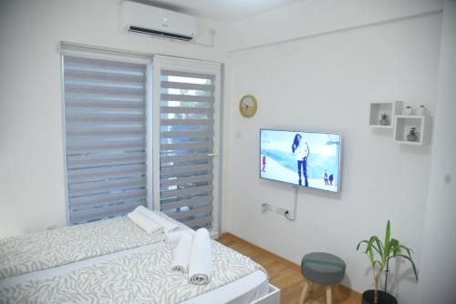um quarto com uma cama e uma televisão na parede em Dekart 2 Apartment em Niš