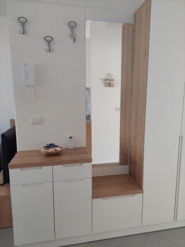 a kitchen with white cabinets and a mirror at Vala Mar apartment- A41 in Durrës