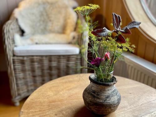 a vase with flowers on a table with a chair at Bledford Chiloé in Castro