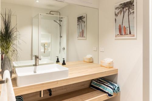 La salle de bains est pourvue d'un lavabo blanc et d'un miroir. dans l'établissement Ocean Retreat 222, à Mount Maunganui