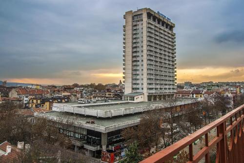 a tall white building next to a city at Plaza Hotel in Varna City