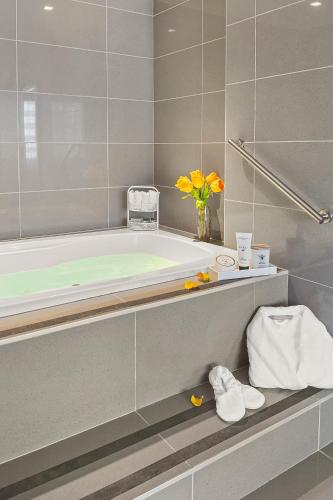 a bathroom with a tub and a vase of flowers at The Armon Stamford Hotel & Conference Center in Stamford