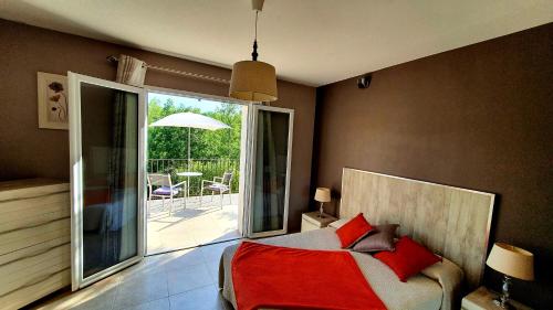 une chambre avec un lit avec des oreillers rouges et un balcon dans l'établissement La Bergeronnette, à Saint-Paul-en-Forêt