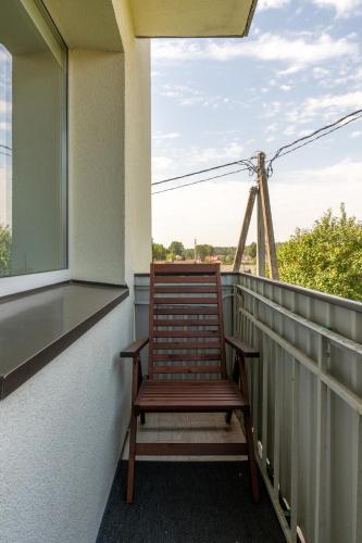 a wooden chair sitting on the balcony of a house at Apartamentai Tytuvėnuose in Tytuvėnai
