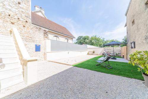 une cour avec une pelouse entre deux bâtiments dans l'établissement Côté Cour, 3 chambres, terrasses, jardin privé avec terrain de pétanque, cave voutée, à Corgoloin