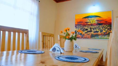 a wooden table with blue plates and a vase of flowers at Osotwa Maasai Hostel in Arusha