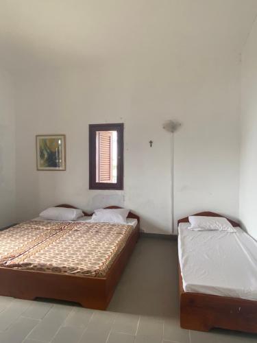 2 bedden in een witte kamer met een raam bij Villa CB village Aby in Aboisso