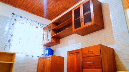 a kitchen with wooden cabinets and a brick wall at Osotwa Maasai Hostel in Arusha