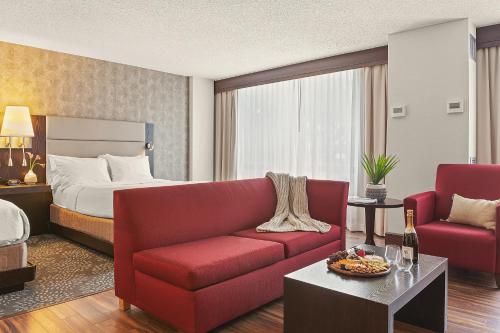 a hotel room with a red couch and a bed at Armon Hotel & Conference Center Stamford CT in Stamford