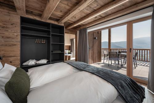 a bedroom with a large bed and a balcony at DILIA Chalets & Apartments in Mühlbach