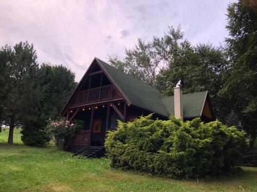 a small wooden cabin with a green roof at Domek Pod Lasem in Trzciana