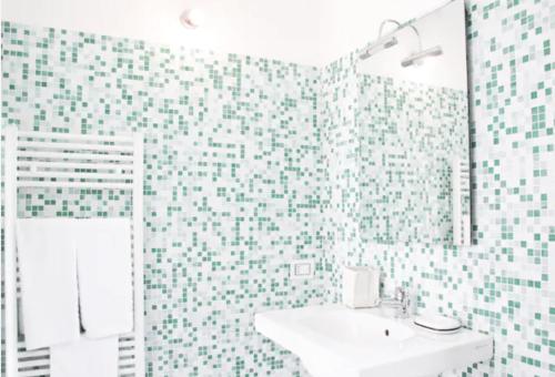 uma casa de banho com paredes em azulejo verde e branco e um lavatório. em Apartments Le Terrazze em Vernazza