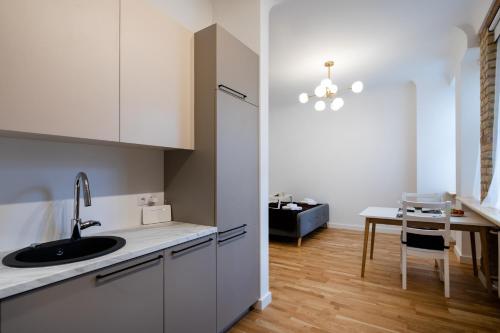 - une cuisine avec des placards blancs, un évier et une table dans l'établissement Brivibas House Design Apartments In City Center, à Riga