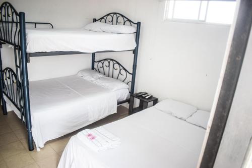 two bunk beds in a room with white sheets at Soga Hostal in Santa Marianita