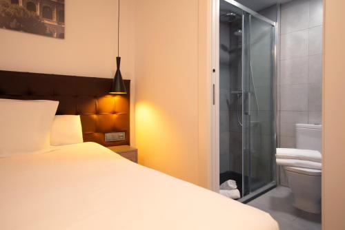 a bedroom with a bed and a glass shower at Woohoo Rooms Hortaleza in Madrid