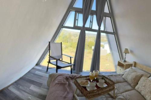 een woonkamer met een bank en een groot raam bij Cabaña Nórdica muy cómoda para unos días de relax in Villa Serrana