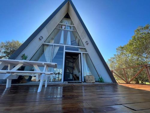 a triangular house with a thatched roof with a wooden deck at Cabaña Nórdica muy cómoda para unos días de relax in Villa Serrana
