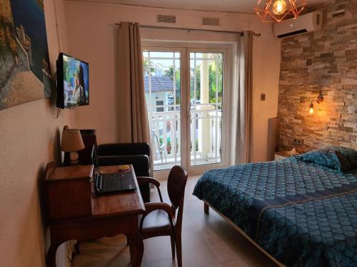 1 dormitorio con cama, escritorio y ventana en Le Bellissima, en Saint-Gilles-les-Bains